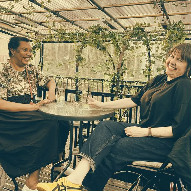 Guests at a terrace table under the vines at By The Bridge